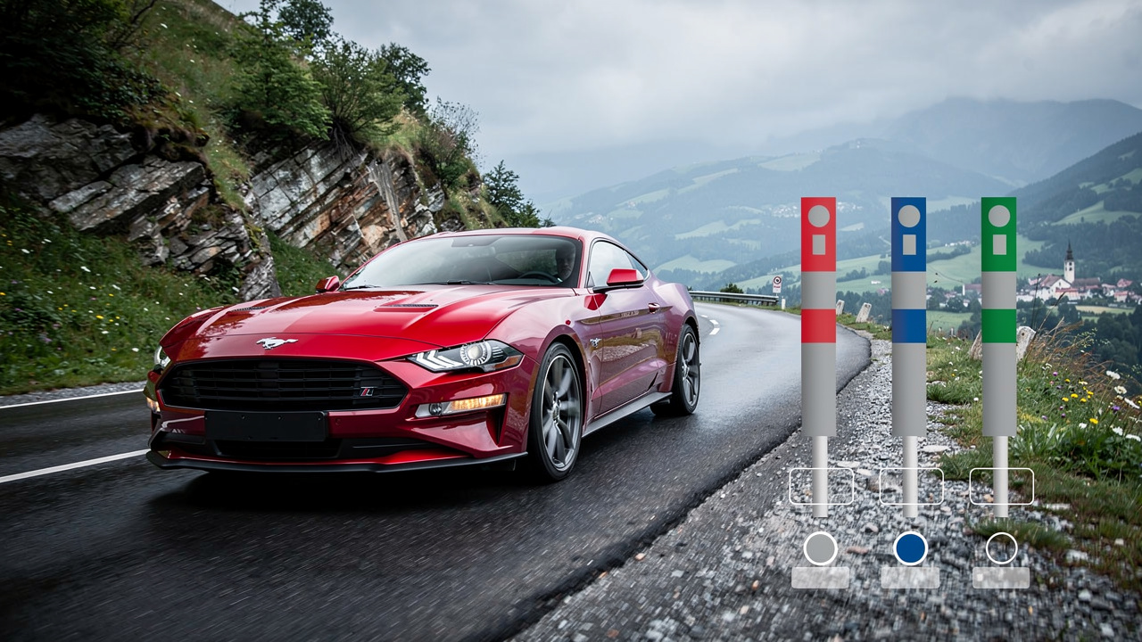Coupé sportif rouge à moteur V8 roulant sur une route européenne, avec trois repères colorés évoquant une comparaison des taxes automobiles entre pays.
